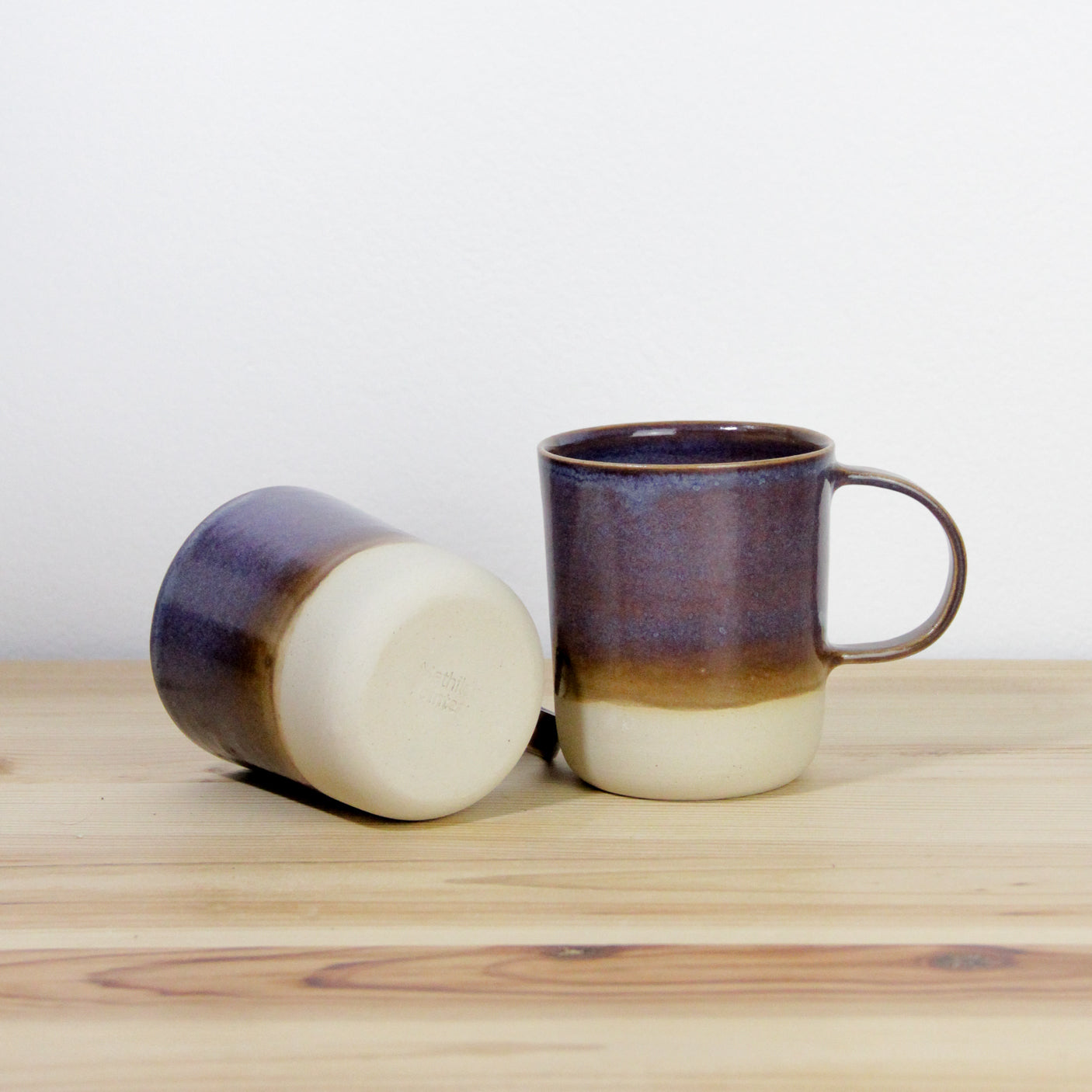Image de deux mugs en grès, vaisselle artisanale fabriquée en France. Les tasses sont brun-violettes.