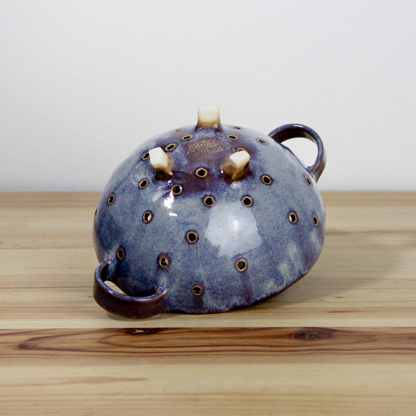 Image d'une petite passoire en céramique de couleur violette.