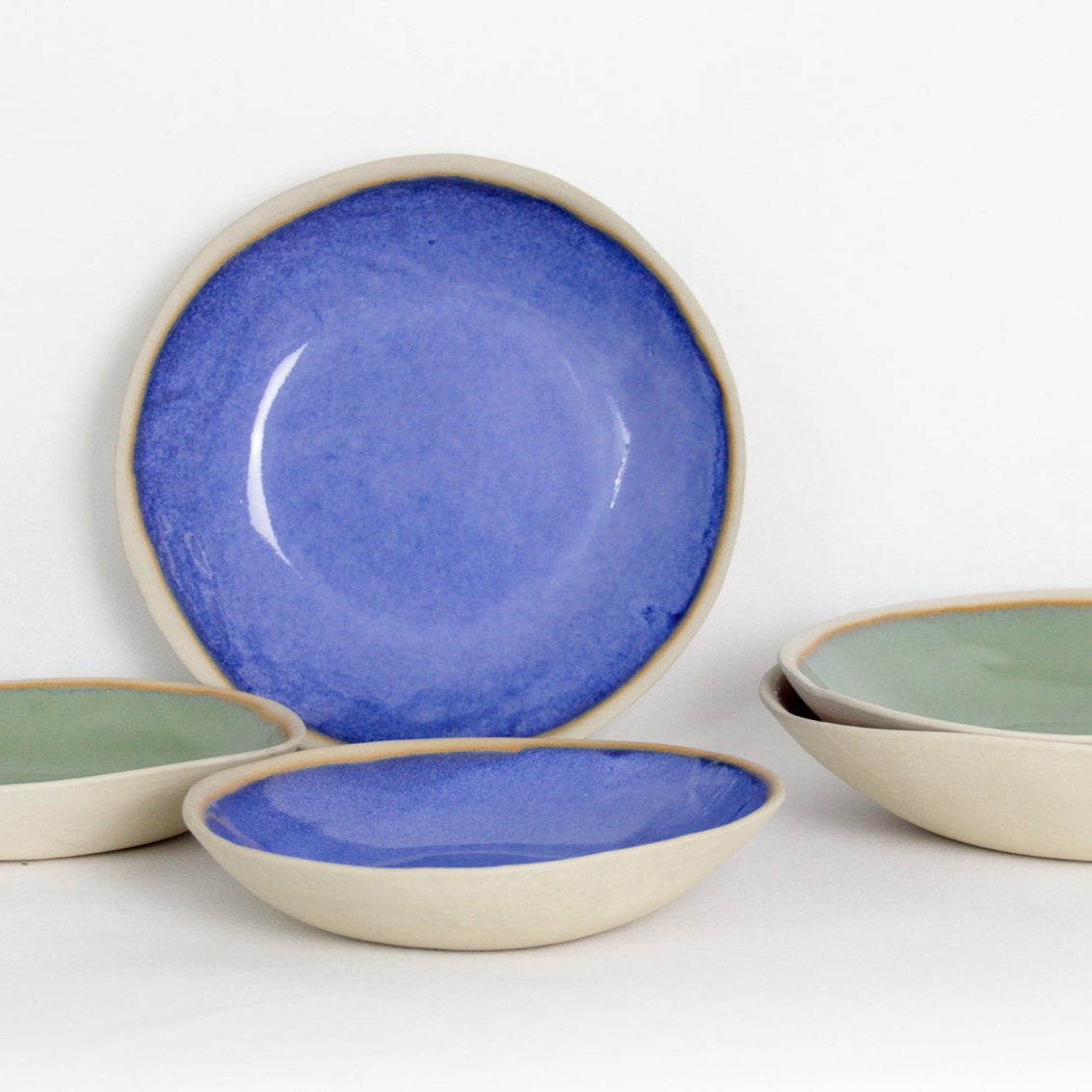Image de plusieurs assiettes creuses colorées en céramique aux formes irrégulières.