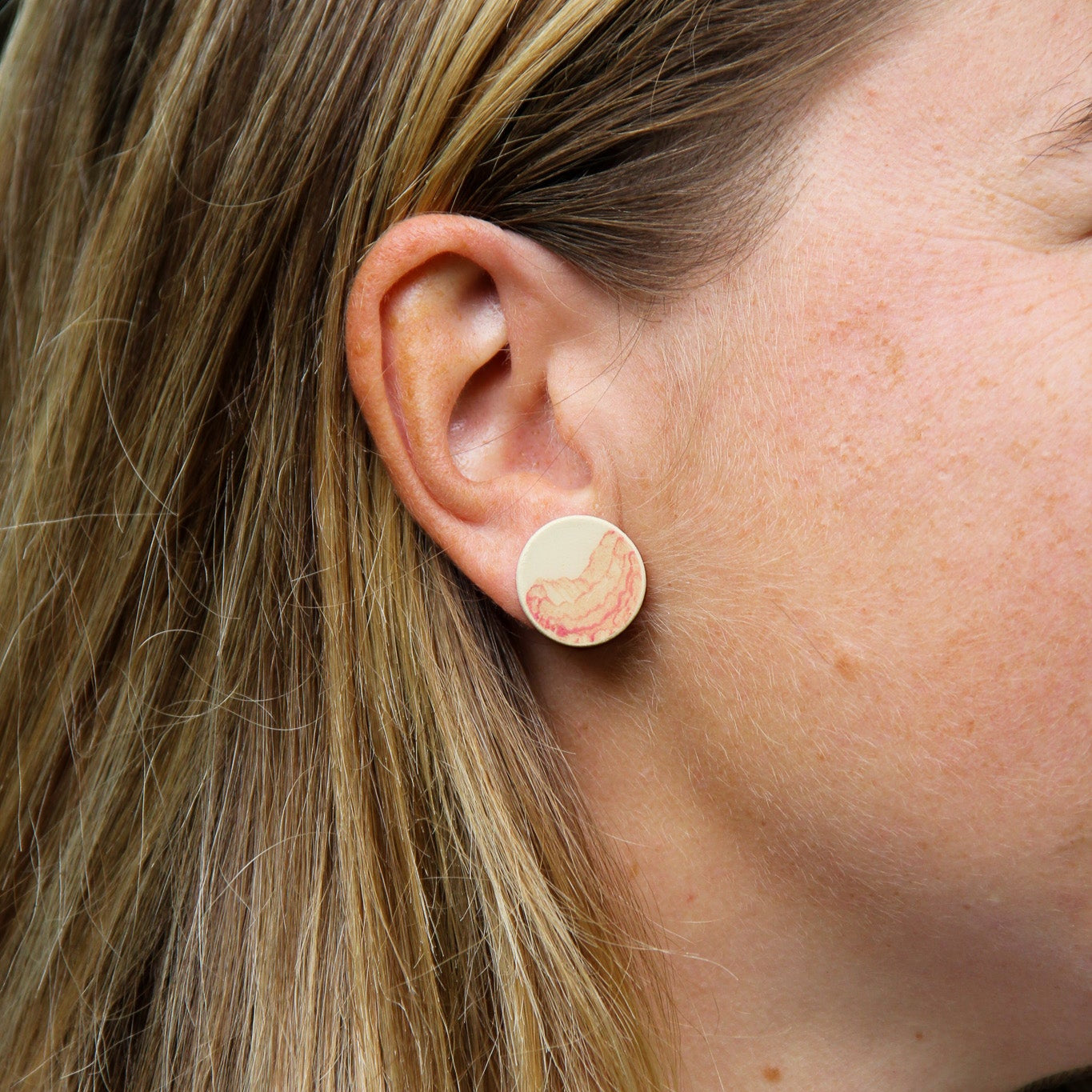 Image d'un zoom sur une boucle d'oreille portée par une femme. Puce d'oreille ronde de 17 mm de diamètre avec accroche en argent.