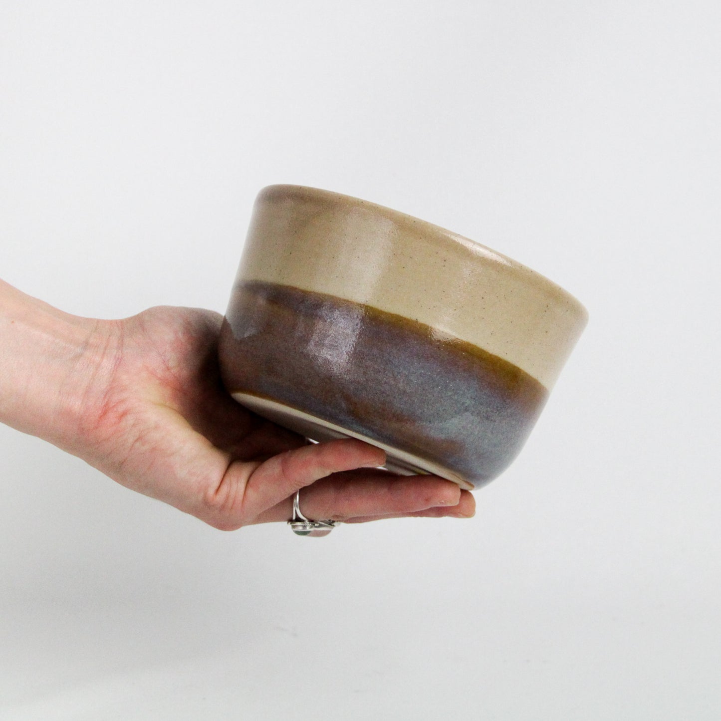 Image d'une main qui tiens un bol en céramique, pièce de vaisselle artisanale