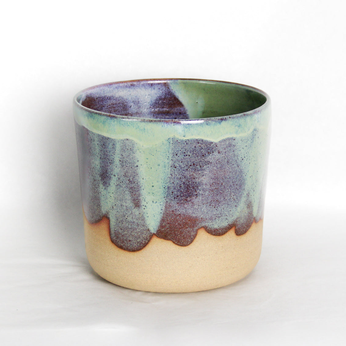 Image d'un cache-pot moderne sur fond blanc. Le pot est vert et émaillé de manière aléatoire.