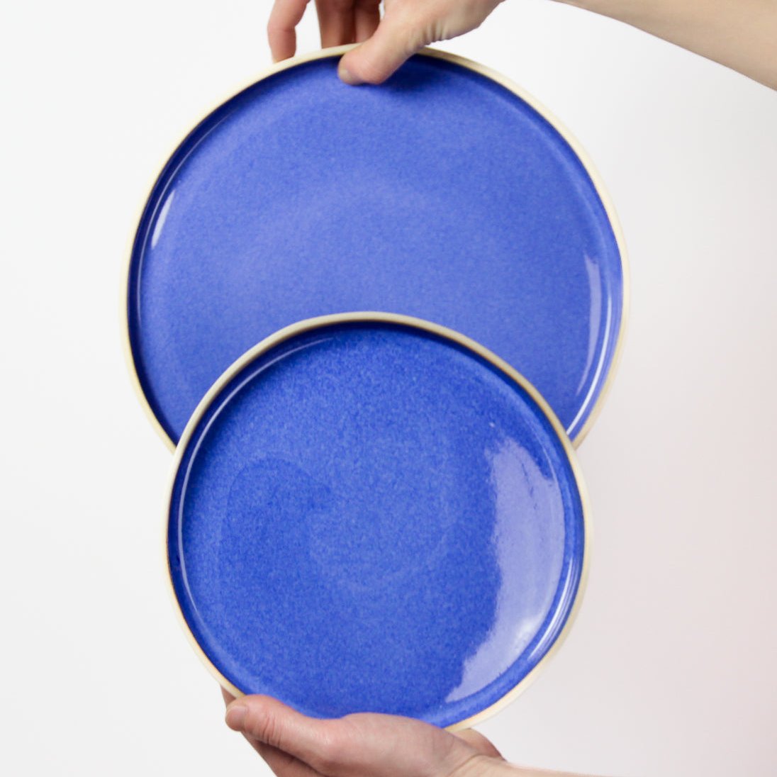 Photo de deux assiettes bleues en grès, une grande et une petite. Ce sont des pièces artisanales