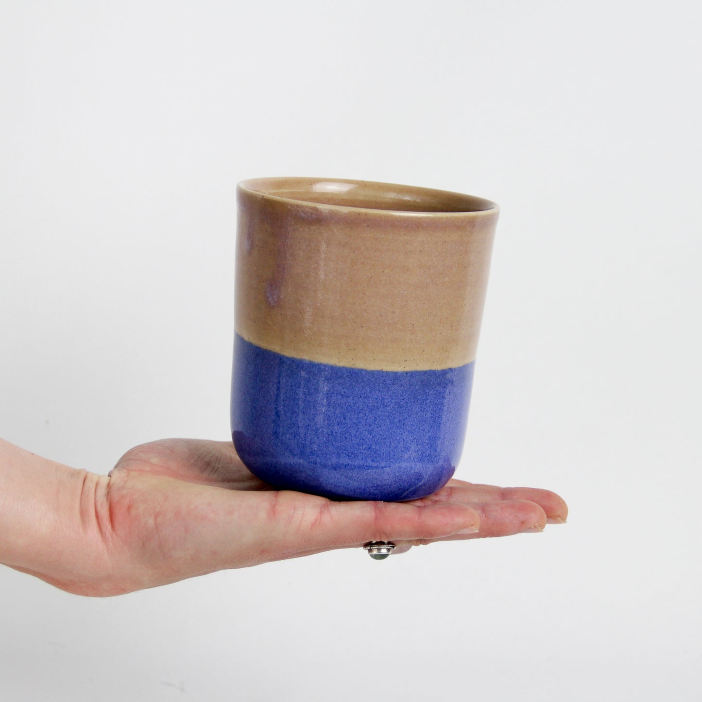Image d'une main qui tient un gobelet en céramique bicolore rose et bleu