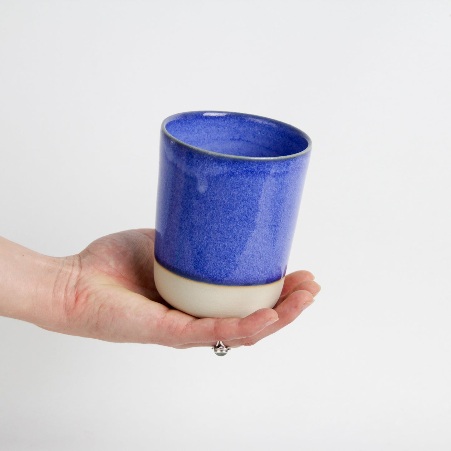 Image d'une main qui tient une grande tasse bleu en céramique artisanale