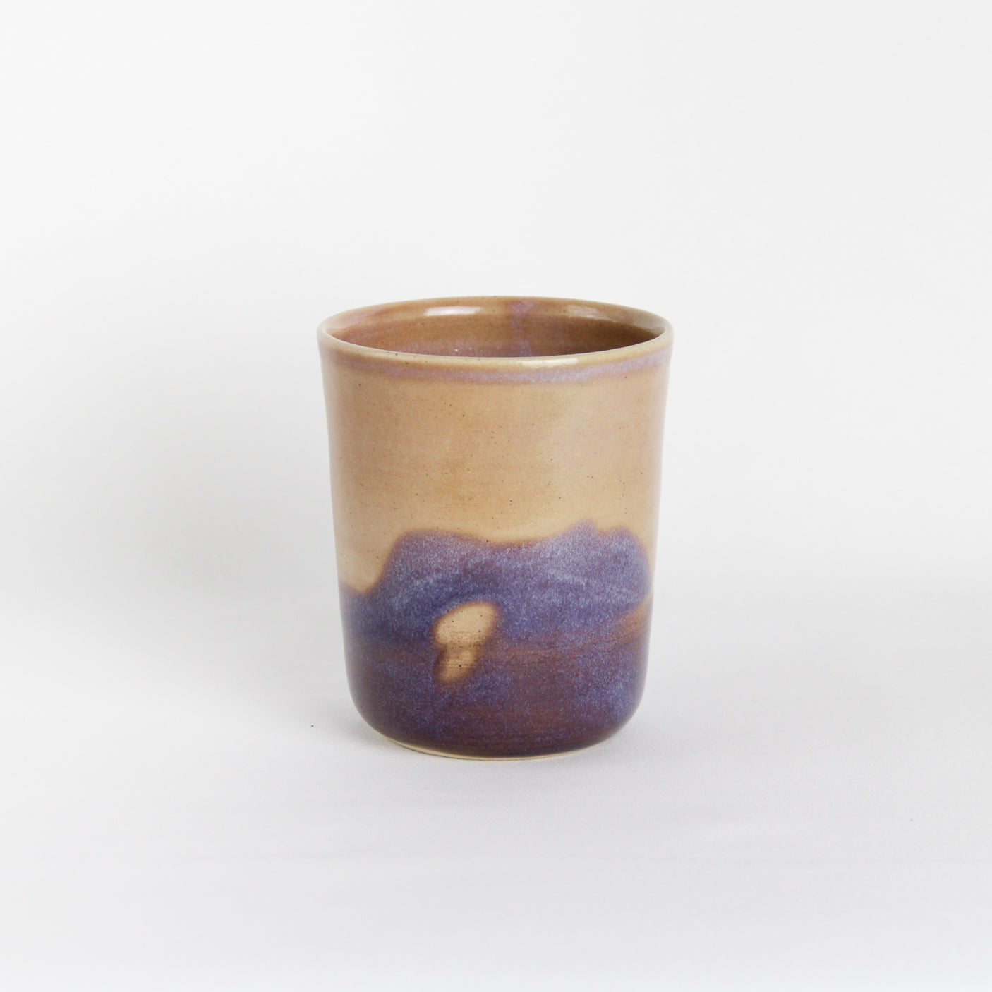 Image d'une gobelet en céramique avec un décor à l'émail unique. La tasse est rose et violette