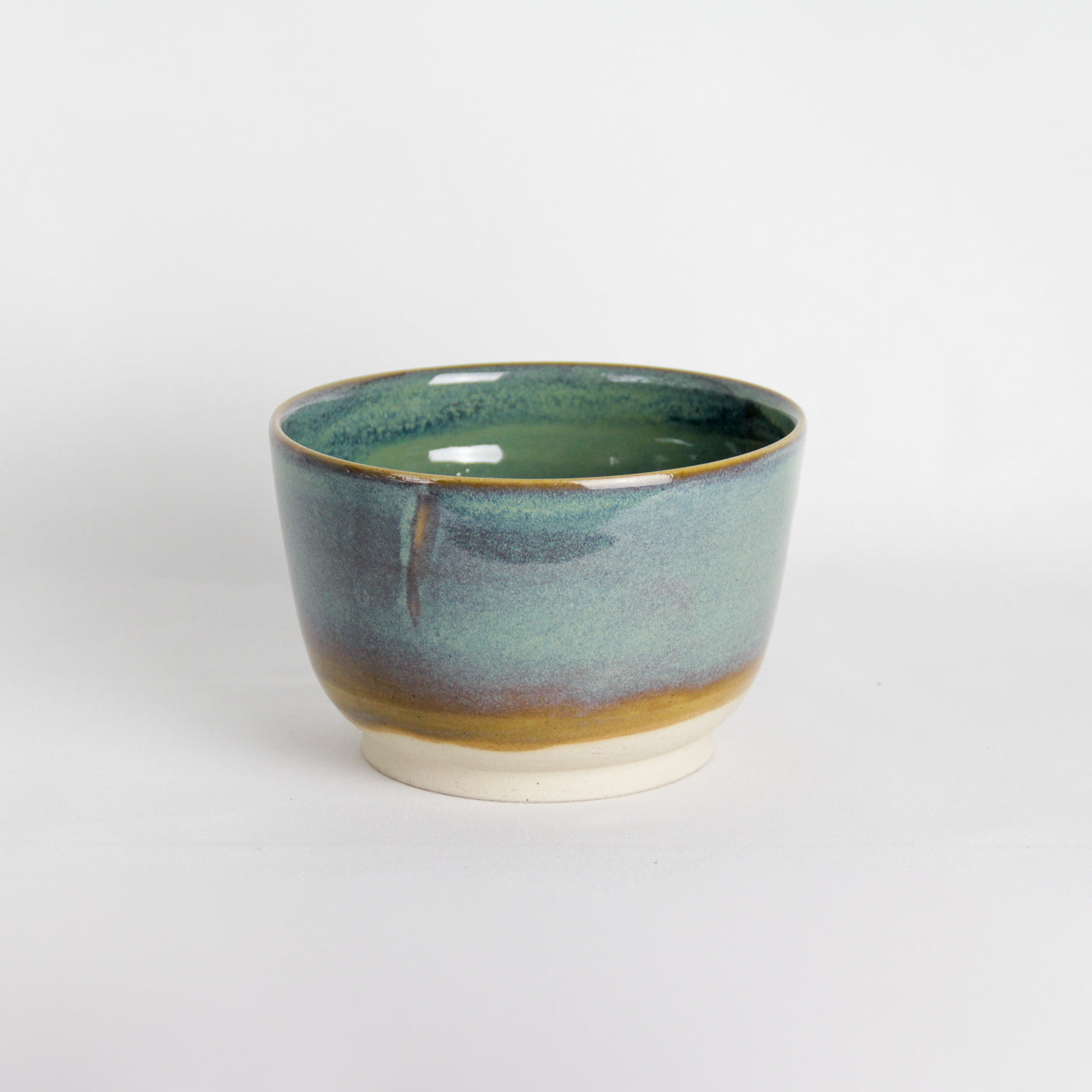 Image d'un grand bol vert sur fond blanc. C'est une pièce en céramique artisanale.