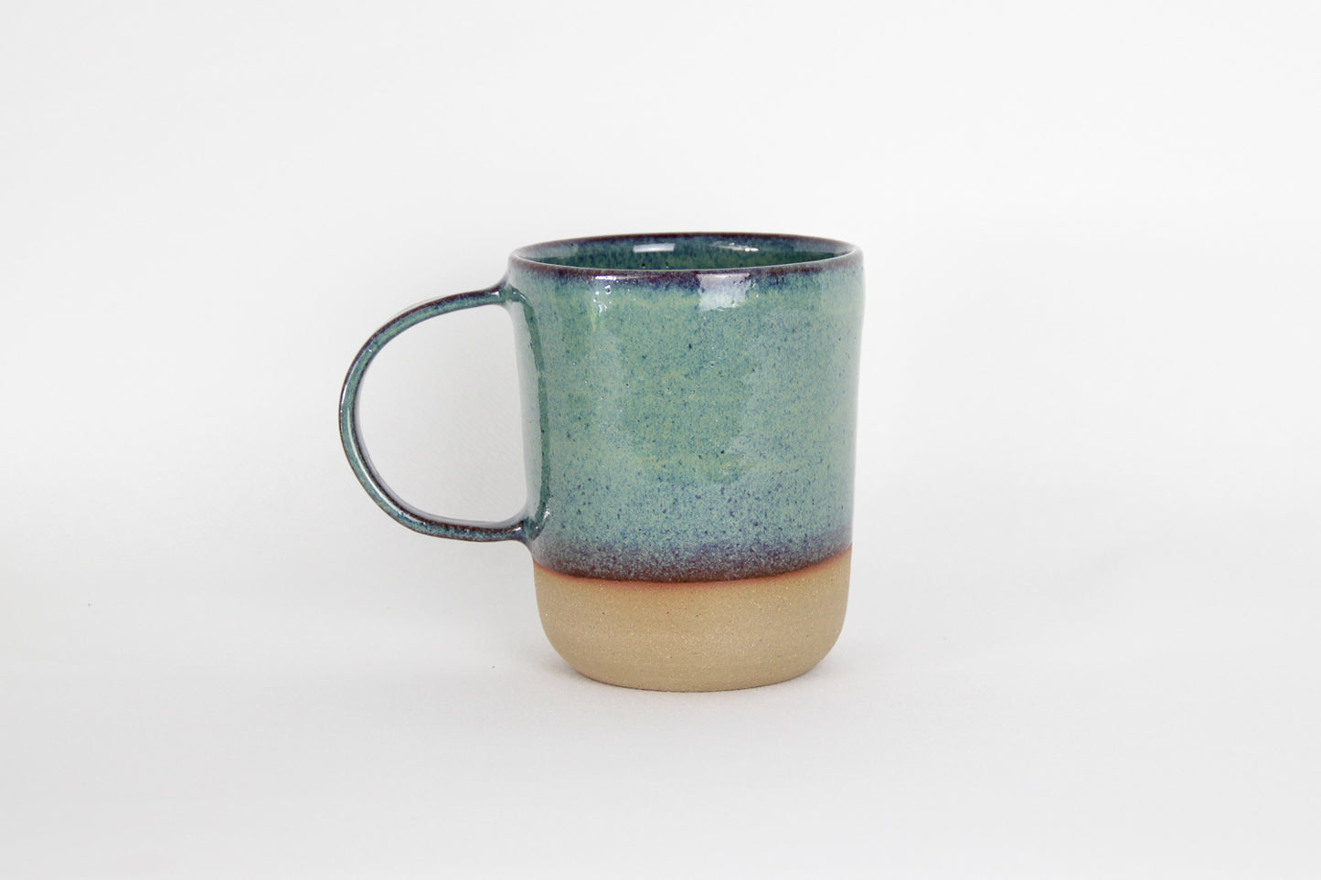 Image d'un grand mug vert sur fond blanc. L'anse est large.