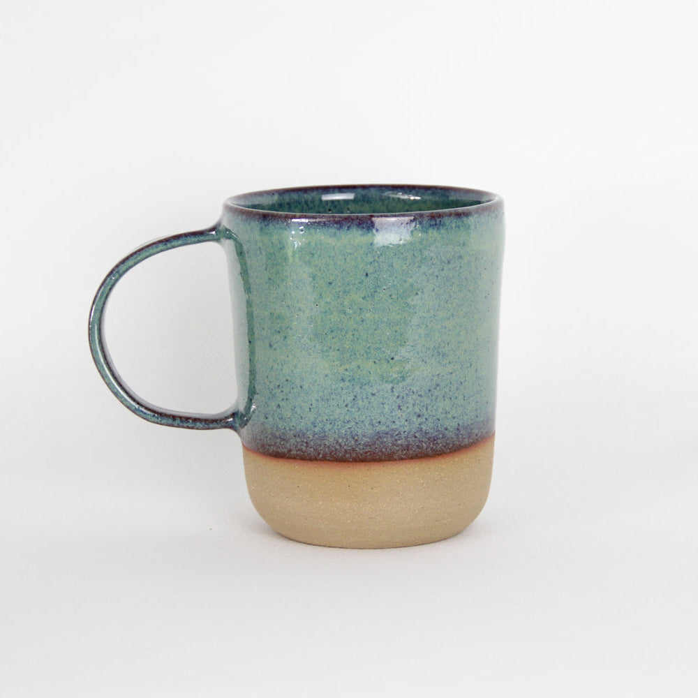 Image d'un grand mug vert sur fond blanc. L'anse est large.