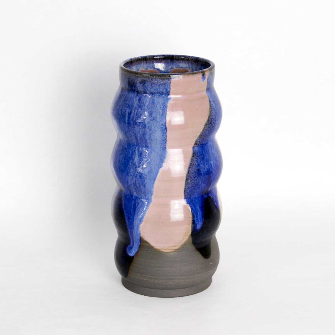 Image d'un grand vase en céramique sur fond blanc. Le vase est rose et bleu, sa forme est irrégulière.