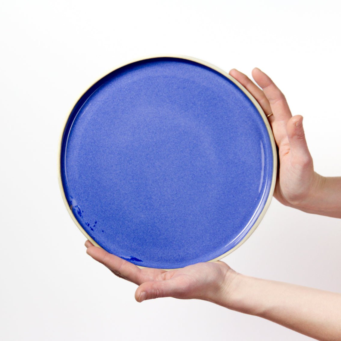 Image d'une belle assiette bleue roi présentée par des mains qui montrent l'échelle de la pièce