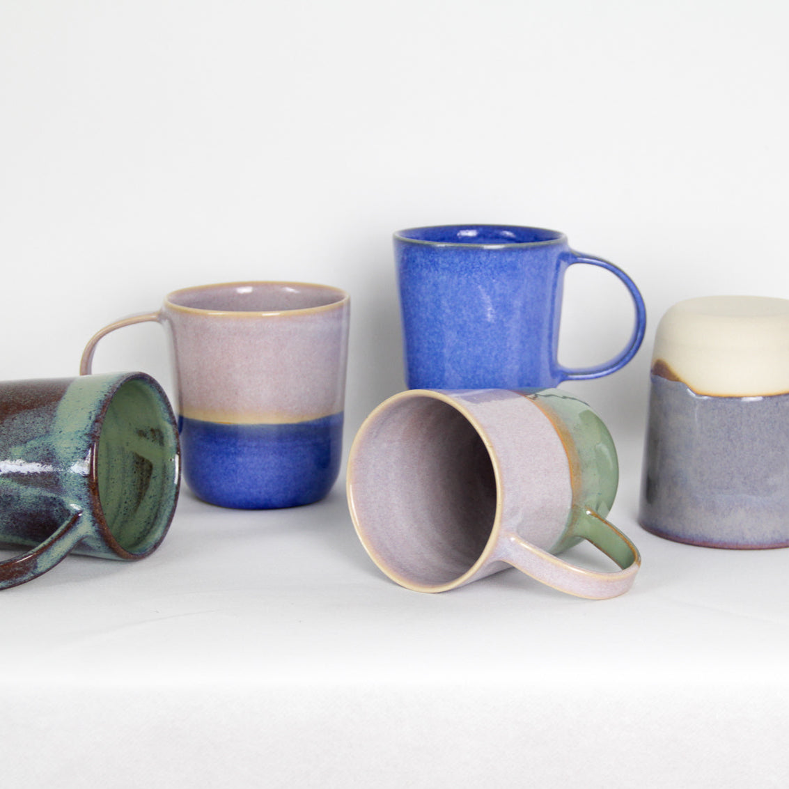Image de cinq mugs de couleurs différentes. Il y a du violet du bleu, du rose et du vert. Certains mugs sont bicolores et d'autres bi-matières. L'anse est grande pour une bonne prise en main. Le format est généreux 500 ml.