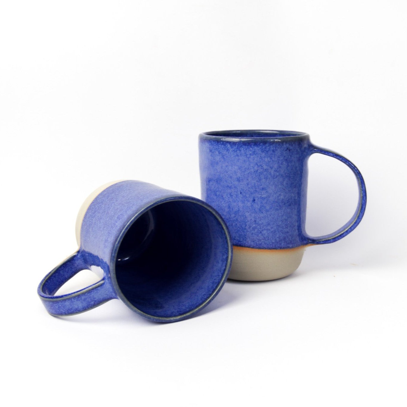 Image de deux grands mugs bleus en céramique. Vaisselle durable pour le quotidien. Ces tasses ont de grandes anses pour une bonne prise en main.