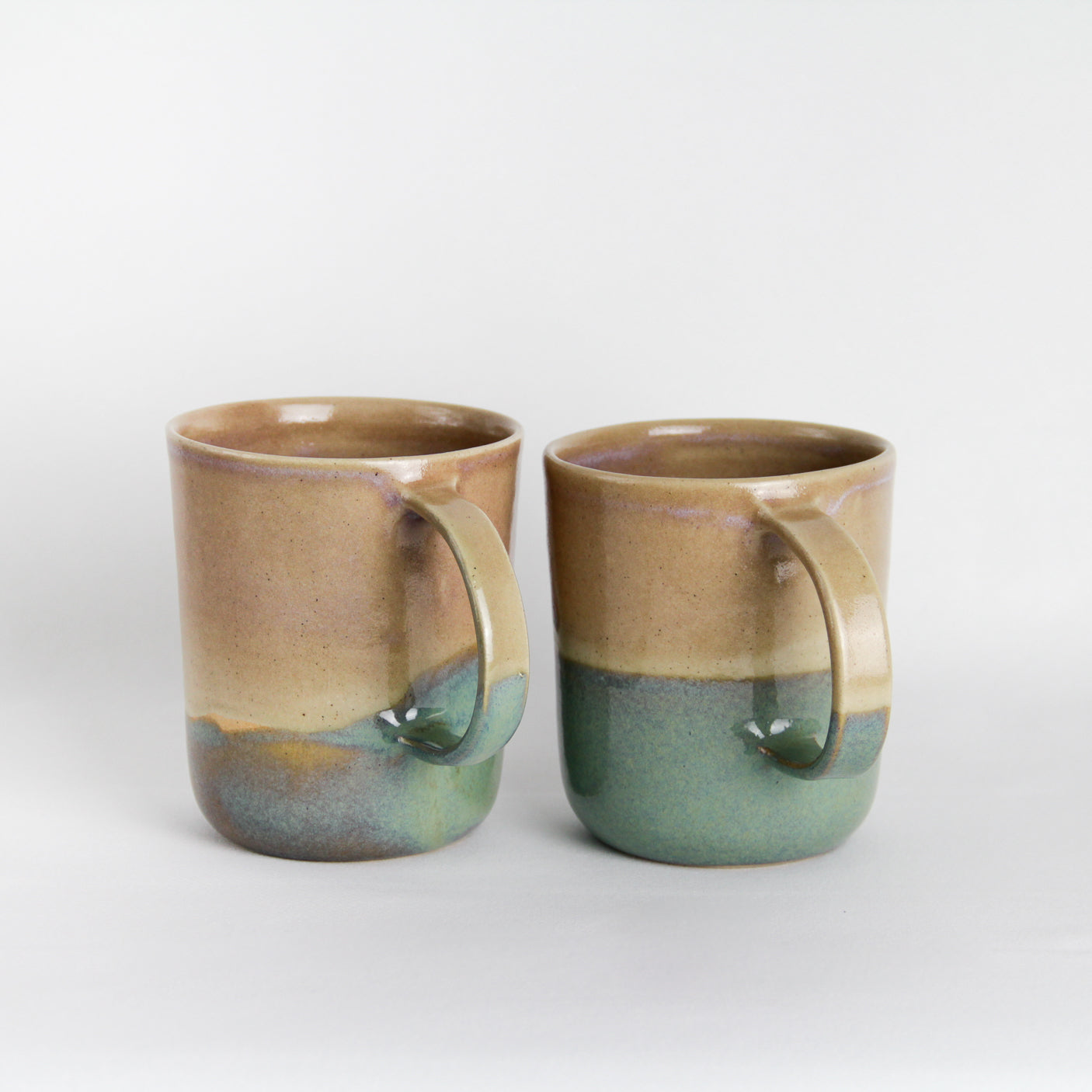 Image de deux grands mugs en céramique qui présentent des variations dans l'application de la couleur. Ce sont des pièces uniques.