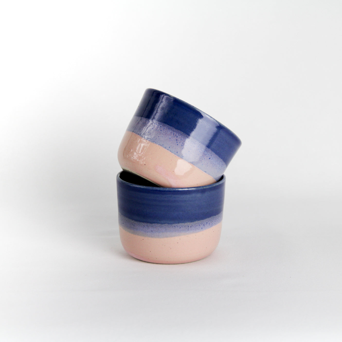 Image de deux petites tasses bicolores roses et bleues en céramique artisanale.