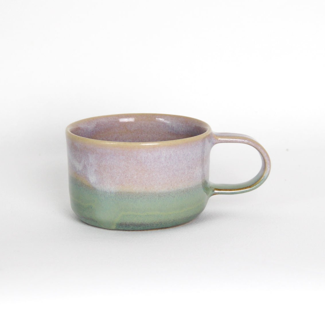 Image d'une tasse avec anse au design minimal. La tasse est en céramique et émaillée avec deux couleurs.