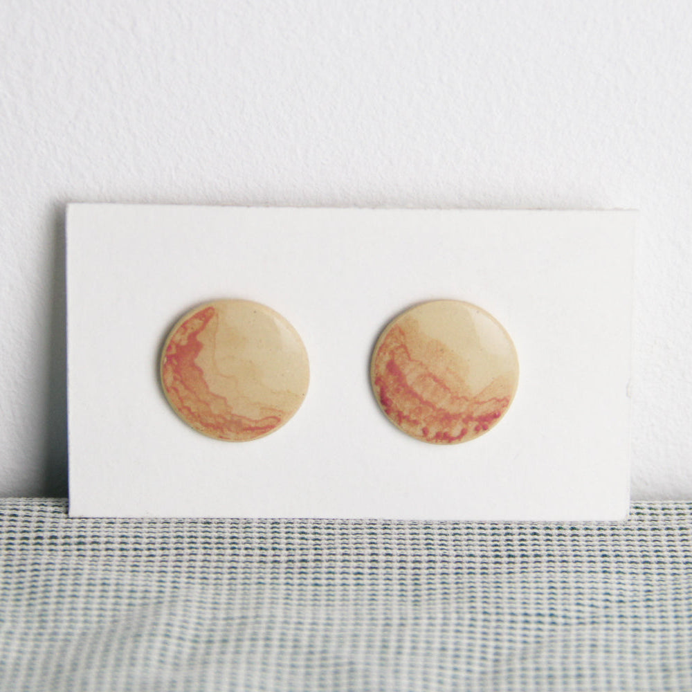 Image d'une paire de boucle d'oreille ronde et plate. Les bijoux sont en céramique