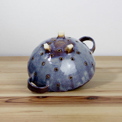 Image d'une petite passoire en céramique de couleur violette.