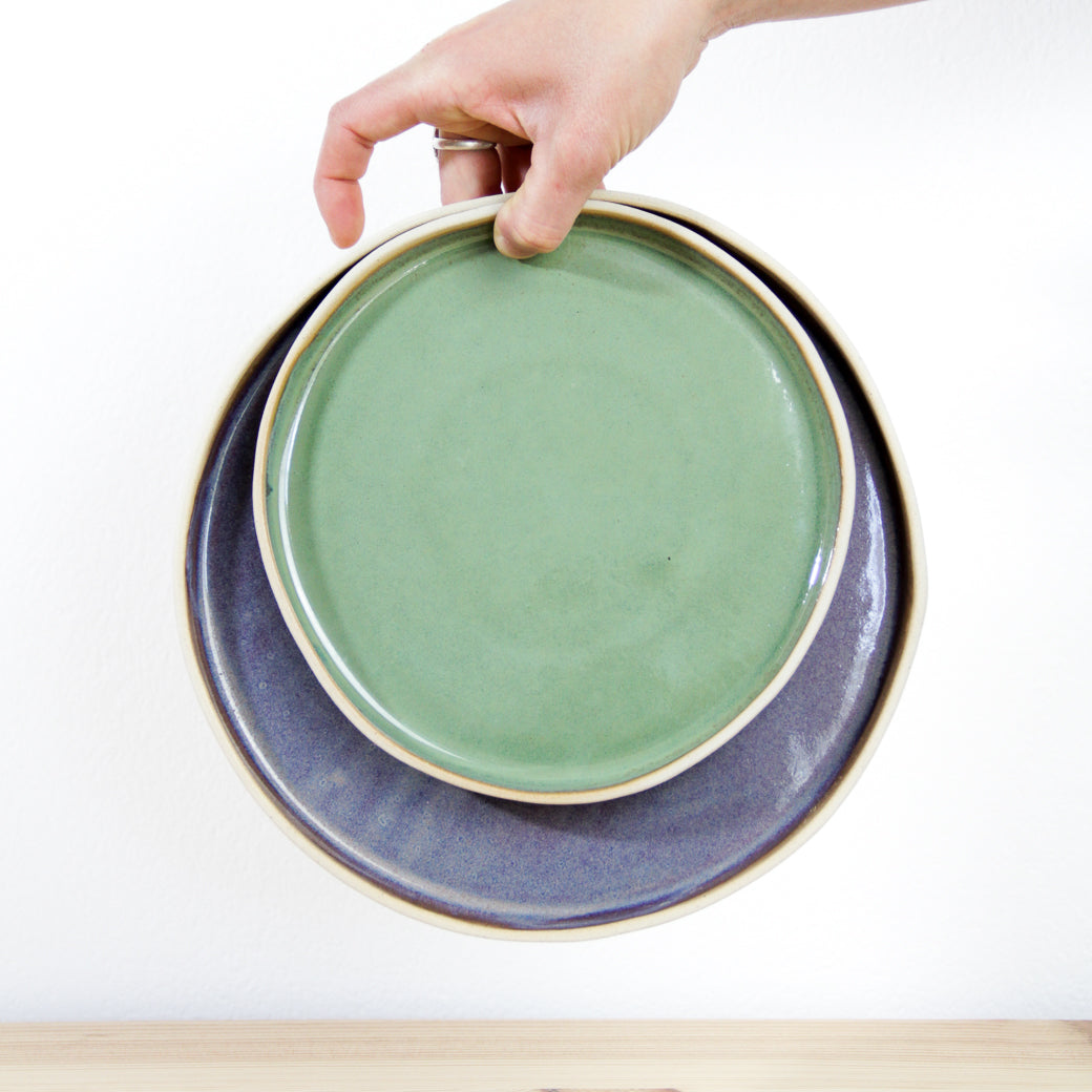 Image d'une main qui tient deux assiettes plates l'une dans l'autre pour nous présenter les deux tailles différentes.