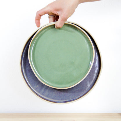 Image d'une main qui tient deux assiettes plates l'une dans l'autre pour nous présenter les deux tailles différentes.