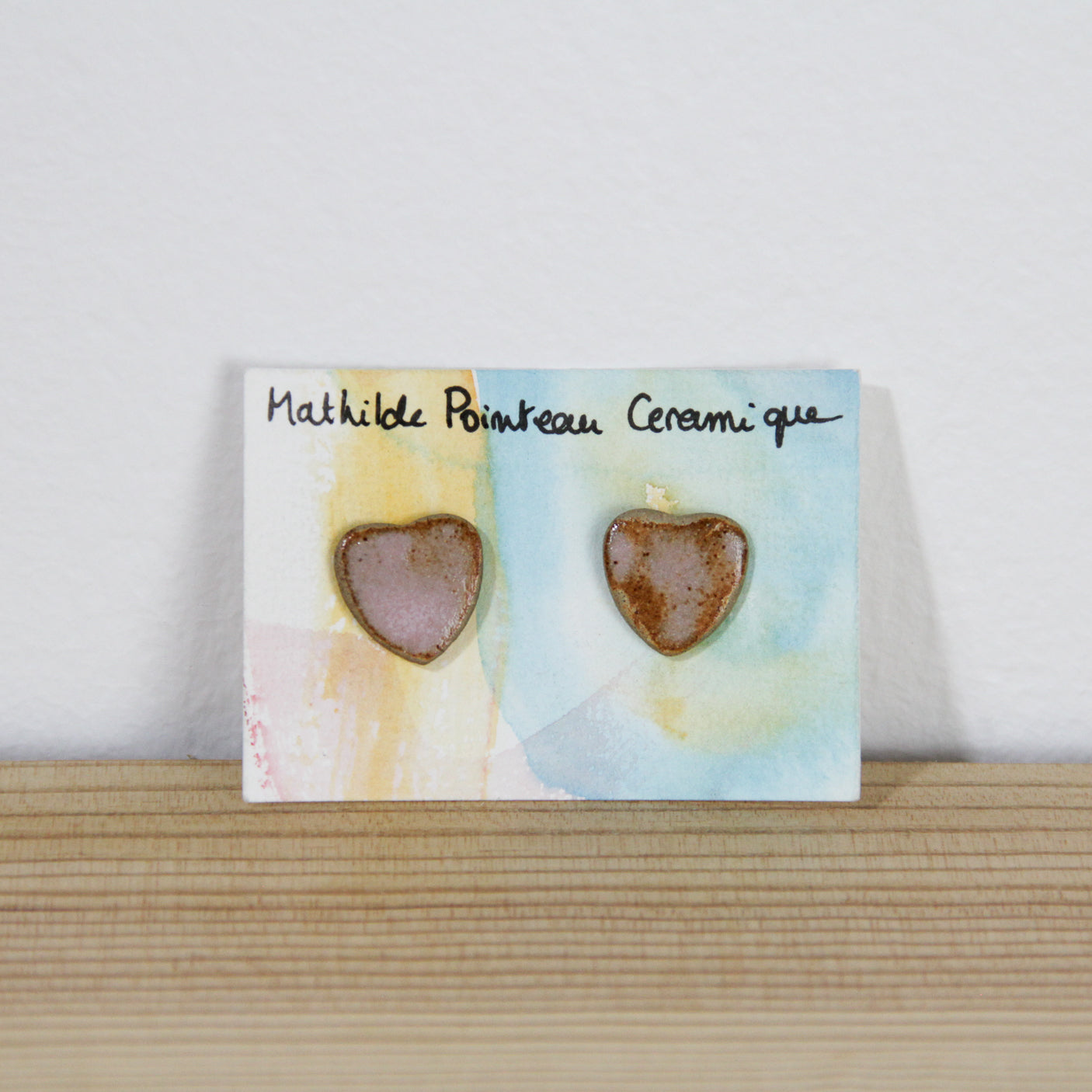 Image d'une paire de boucles d'oreilles rose en forme de coeur. Bijoux en céramique fabriqué à la main. 