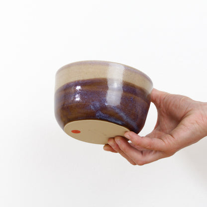 Image d'un bol en grès bicolore rose et violet. Une main le tient et nous montre sa taille.