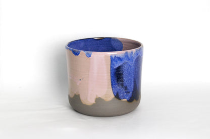 Image d'un cache pot sur fond blanc. L'objet est en céramique, il est émaillé en rose et bleu