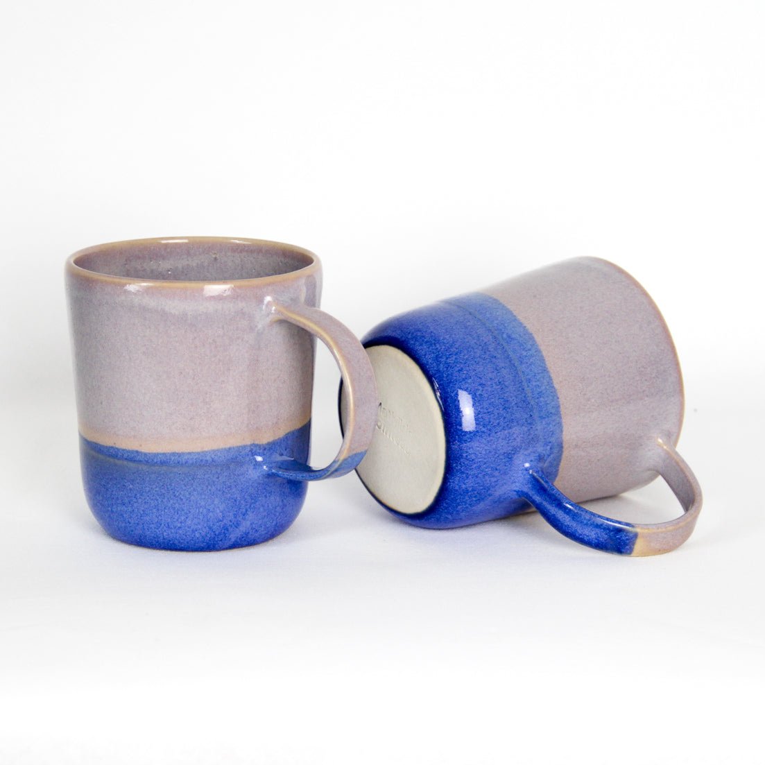 Image de deux mugs en céramique. Ils sont roses et bleus avec une grande anse pour une bonne prise en main. Le style bicolore apporte du peps aux produits.