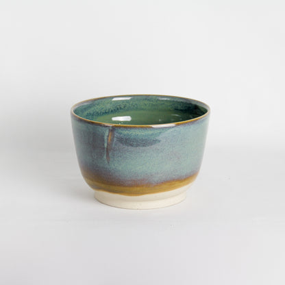 Image d'un grand bol vert sur fond blanc. C'est une pièce en céramique artisanale.