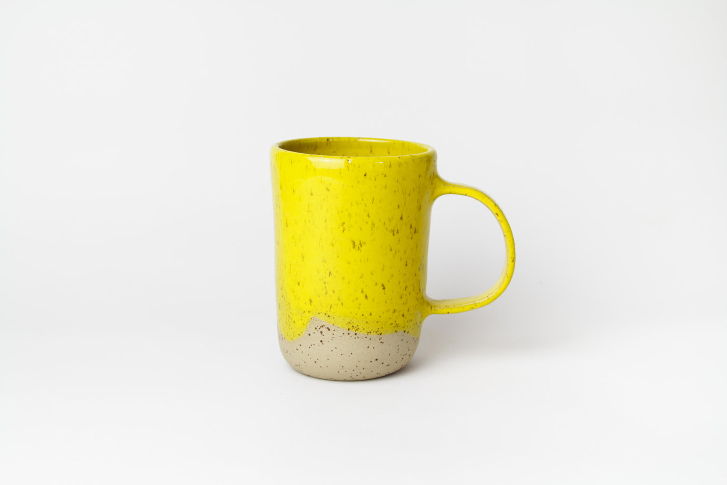 Image d'un grand mug en céramique sur fond blanc. Il est de couleur jaune et l'anse est large pour une bonne prise en main.