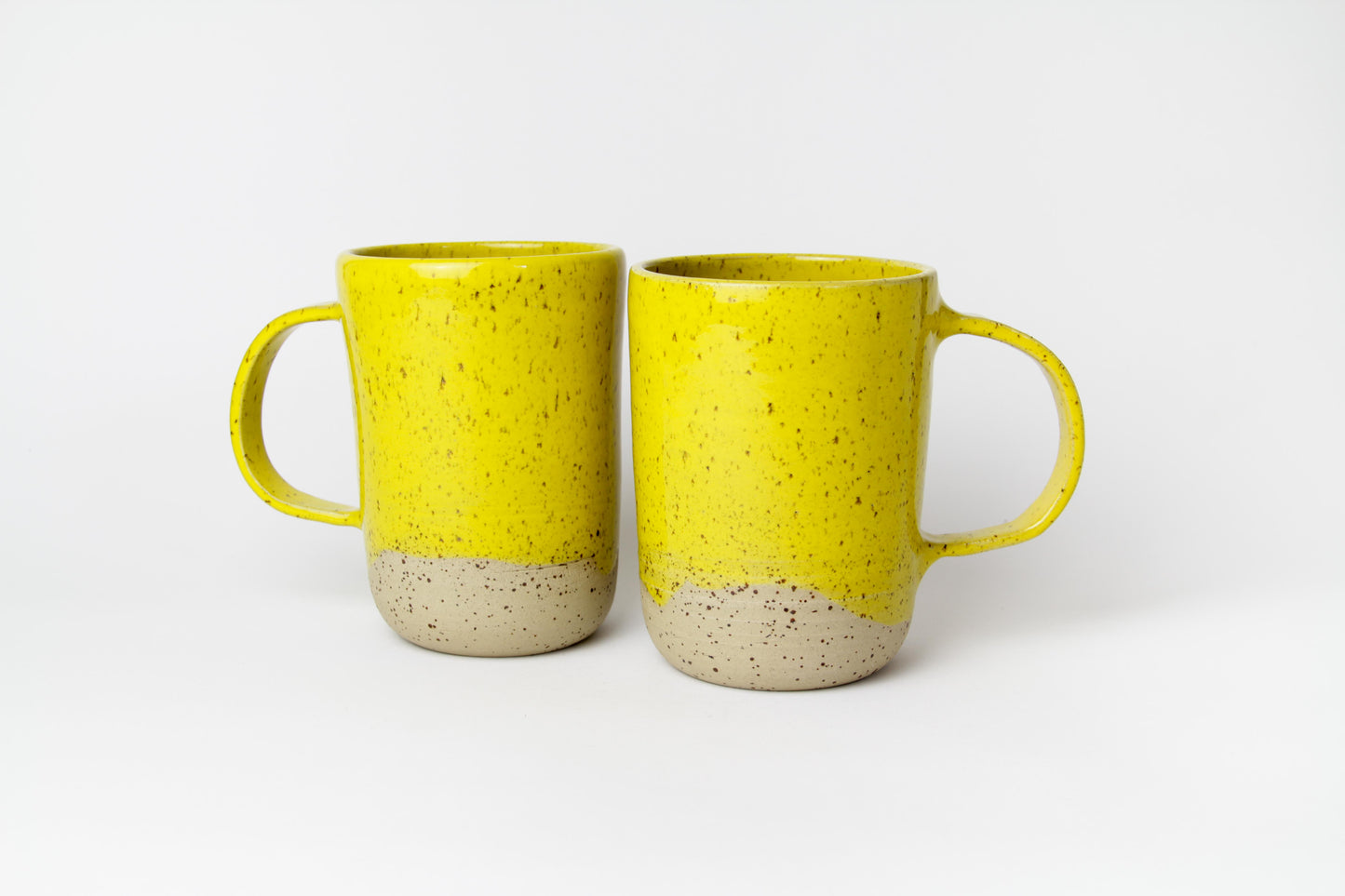 Image de deux grands mugs en céramique de couleur jaune avec une grande anse.