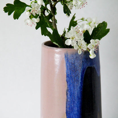 Image d'un détail de vase en céramique artisanale. On observe la superposition des émaux qui apportent une singularité particulière à l'objet. Le vase contient des fleurs.