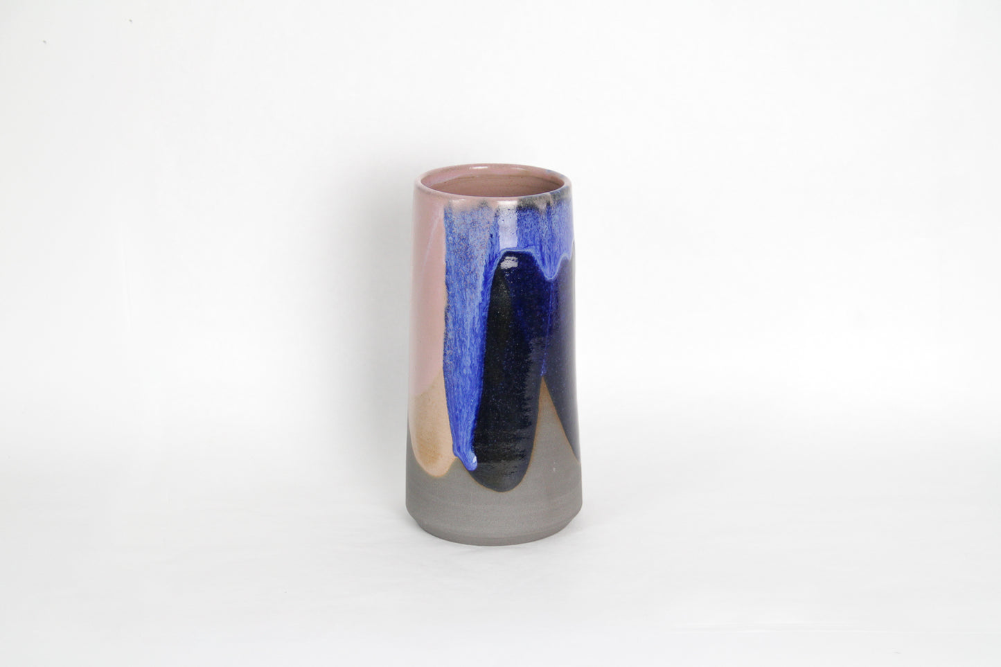 Image d'un vase en grès foncé. Il est émaillé avec du rose et du bleu. Sa forme volcanique est moderne et design.