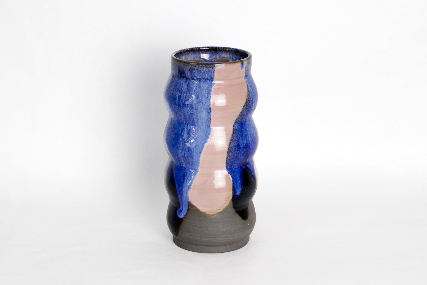 Image d'un grand vase en céramique sur fond blanc. Le vase est rose et bleu, sa forme est irrégulière.