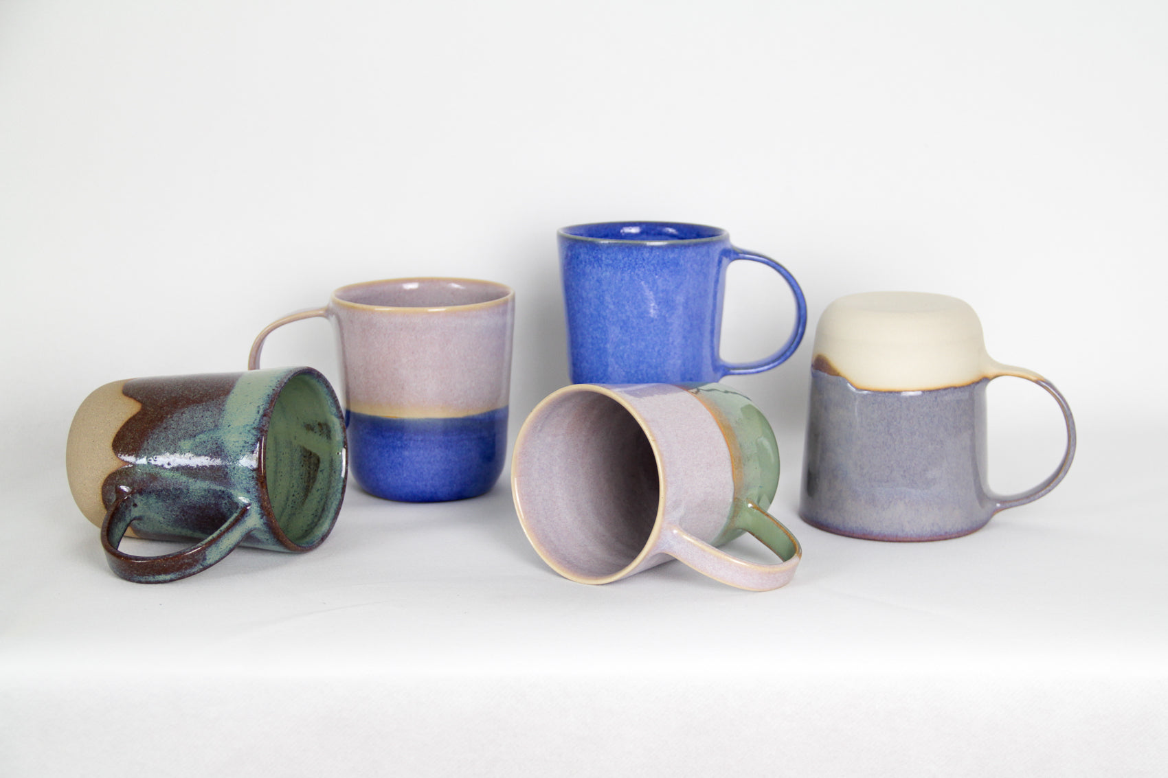 Image de cinq mugs de couleurs différentes. Il y a du violet du bleu, du rose et du vert. Certains mugs sont bicolores et d'autres bi-matières. L'anse est grande pour une bonne prise en main. Le format est généreux 500 ml.