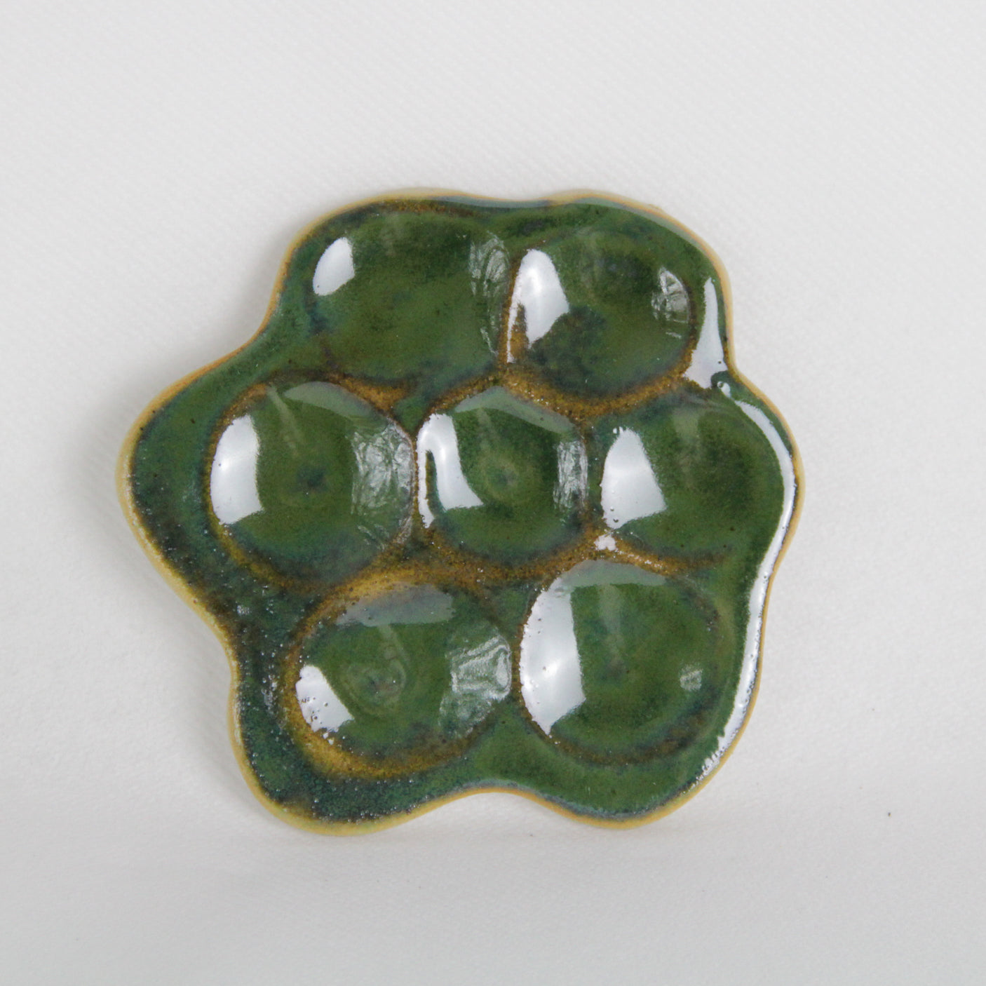 Image d'une pièce verte en céramique en forme de marguerite. Fabrication artisanale