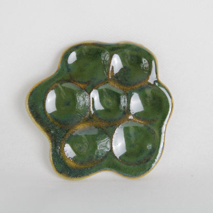 Image d'une pièce verte en céramique en forme de marguerite. Fabrication artisanale