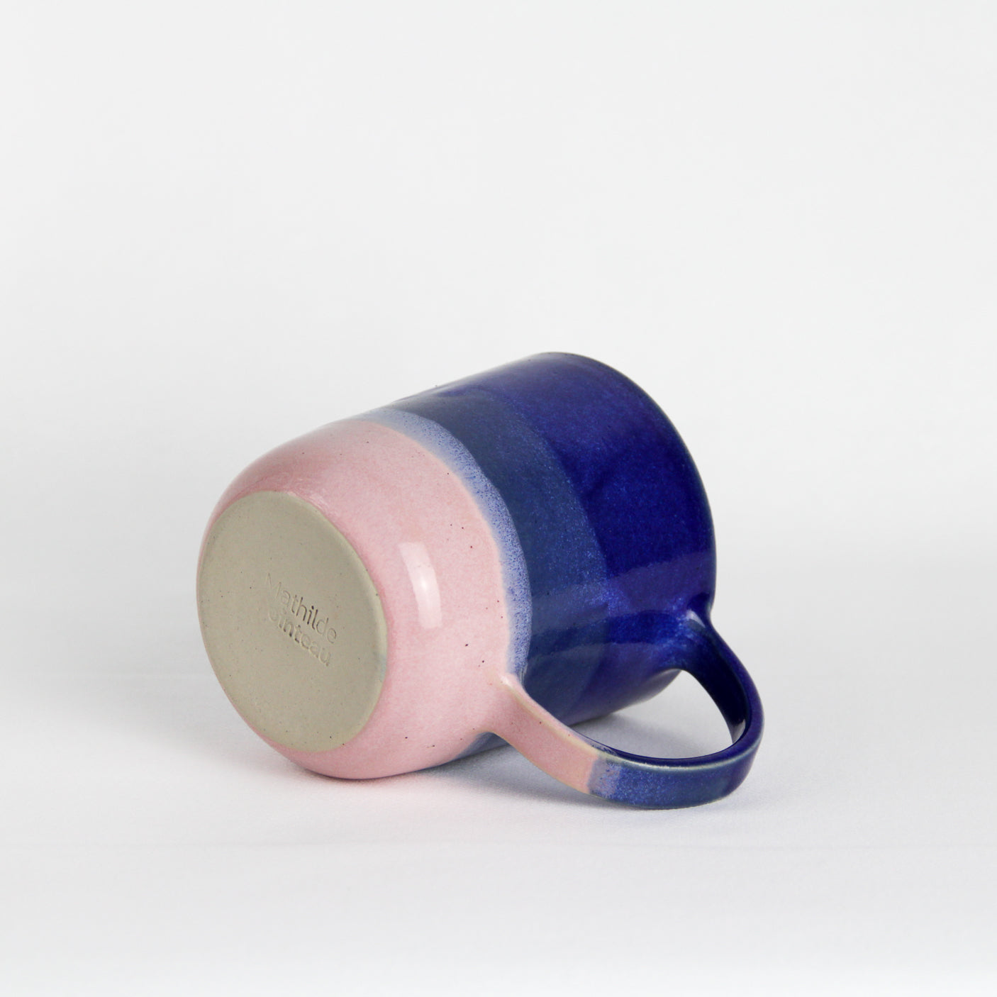 Image d'une mug rose et bleu en céramiquevvu de dessous avec une grande anse.