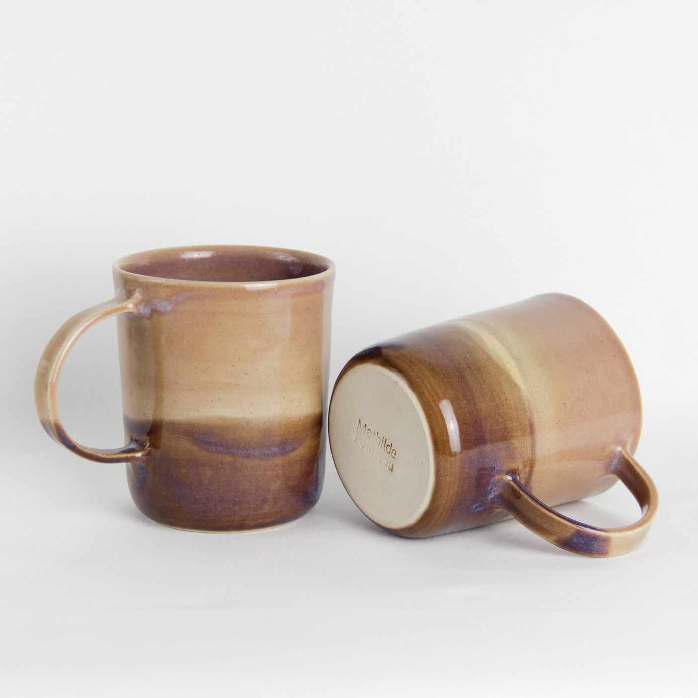 Image de deux grandes tasses en grès clair émaillées de deux couleurs différentes en rose et brun.