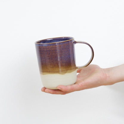 Image d'une main qui présente un mug en céramique artisanale