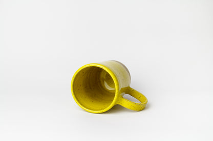 Image d'un grand mug en grès jaune posé sur le côté pour visualiser la forme du produit. Grande contenance de 500 ml et grande anse.