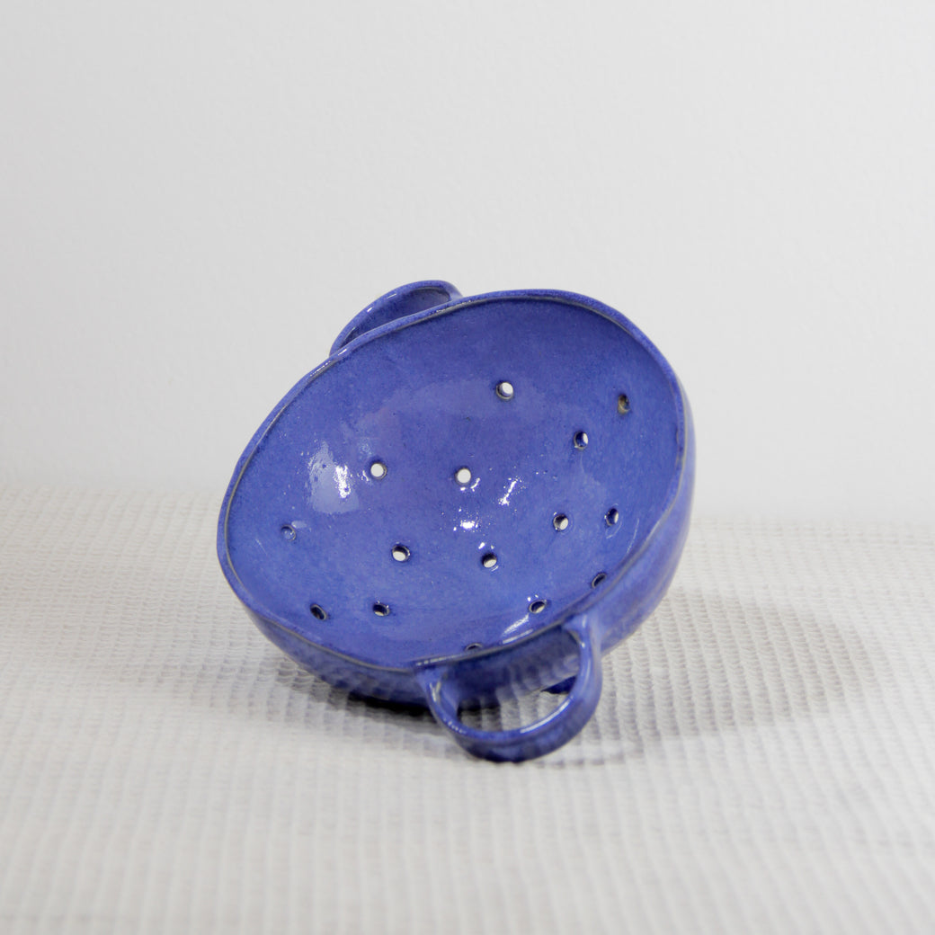 Image d'une petite passoire bleue roi en céramique artisanale modelée à la main