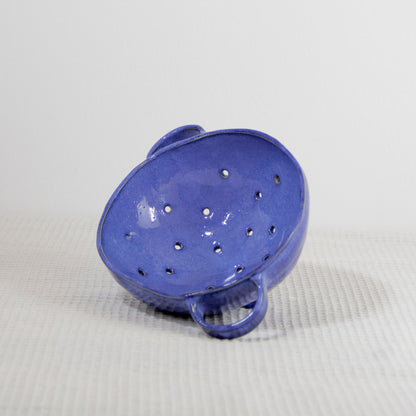 Image d'une petite passoire bleue roi en céramique artisanale modelée à la main