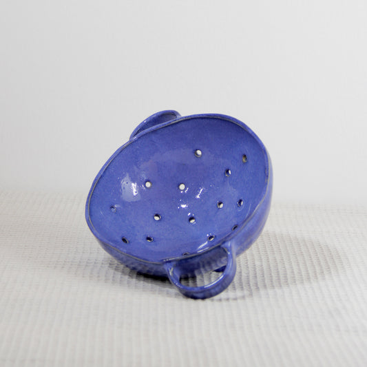 Image d'une petite passoire bleue roi en céramique artisanale modelée à la main