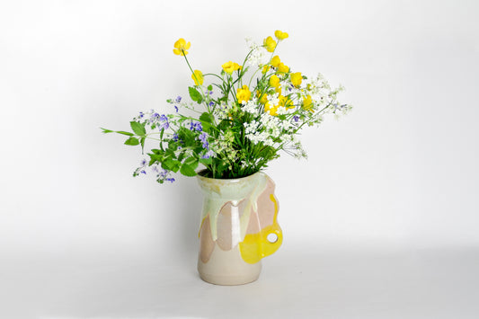 Image d'un petit vase en céramique aux couleurs vives. Le vase contient un joli bouquet de fleurs des champs.