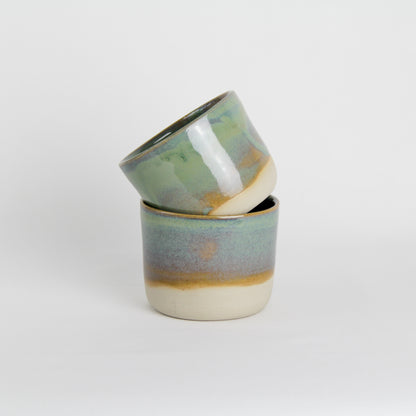Image de deux tasses émaillées en vert. Ce sont des petites tasses à café pour le quotidien.