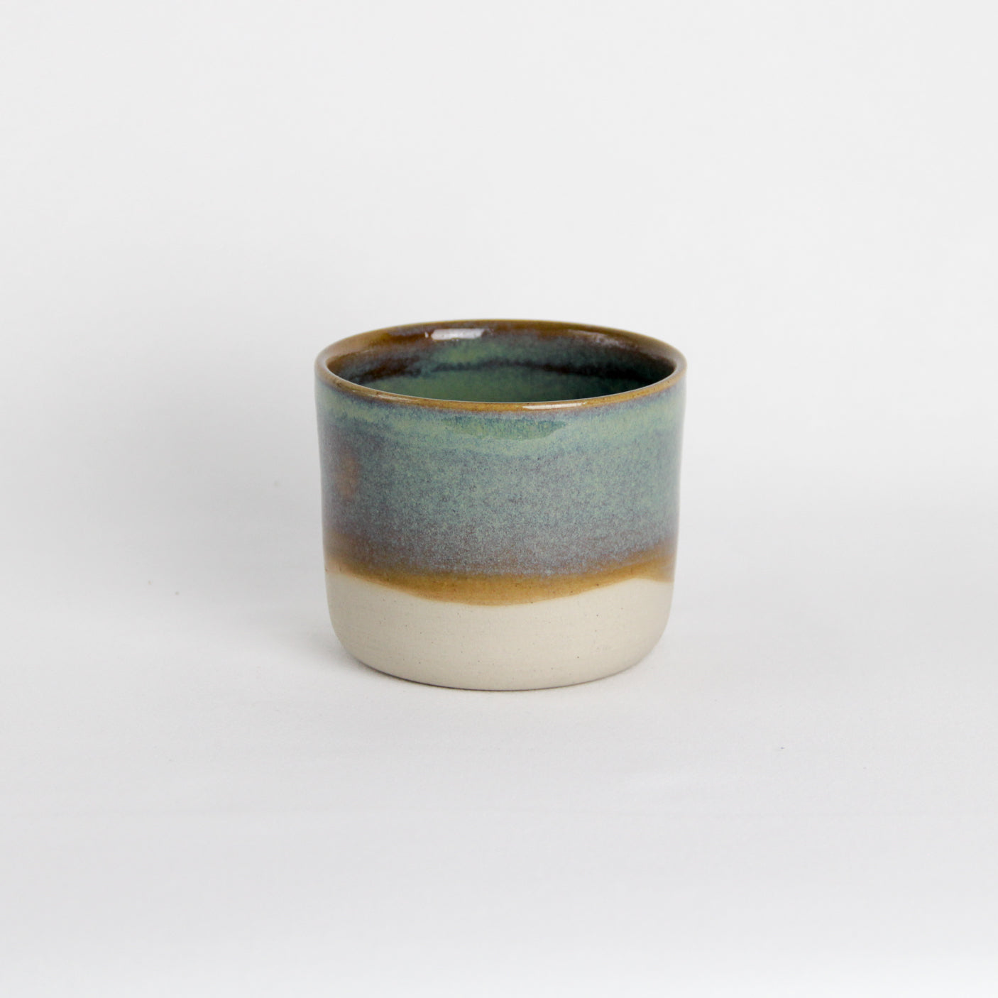 Image d'une petite tasse en grès de couleur verte. La pièce est bi-matière.