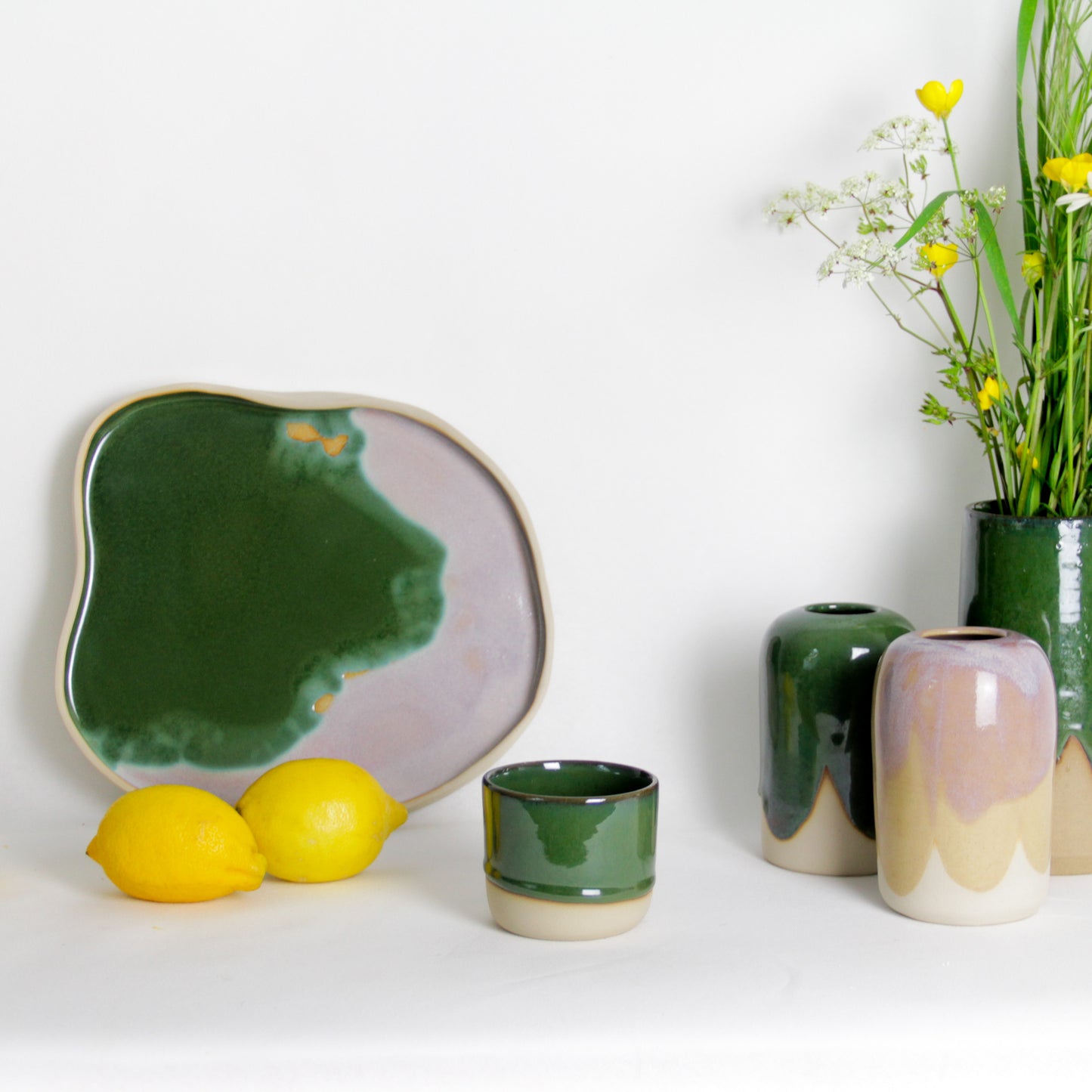 Image d'un plateau, de soliflores et d'une tasse en céramique artisanale. Présentation de la collection verte foncée.