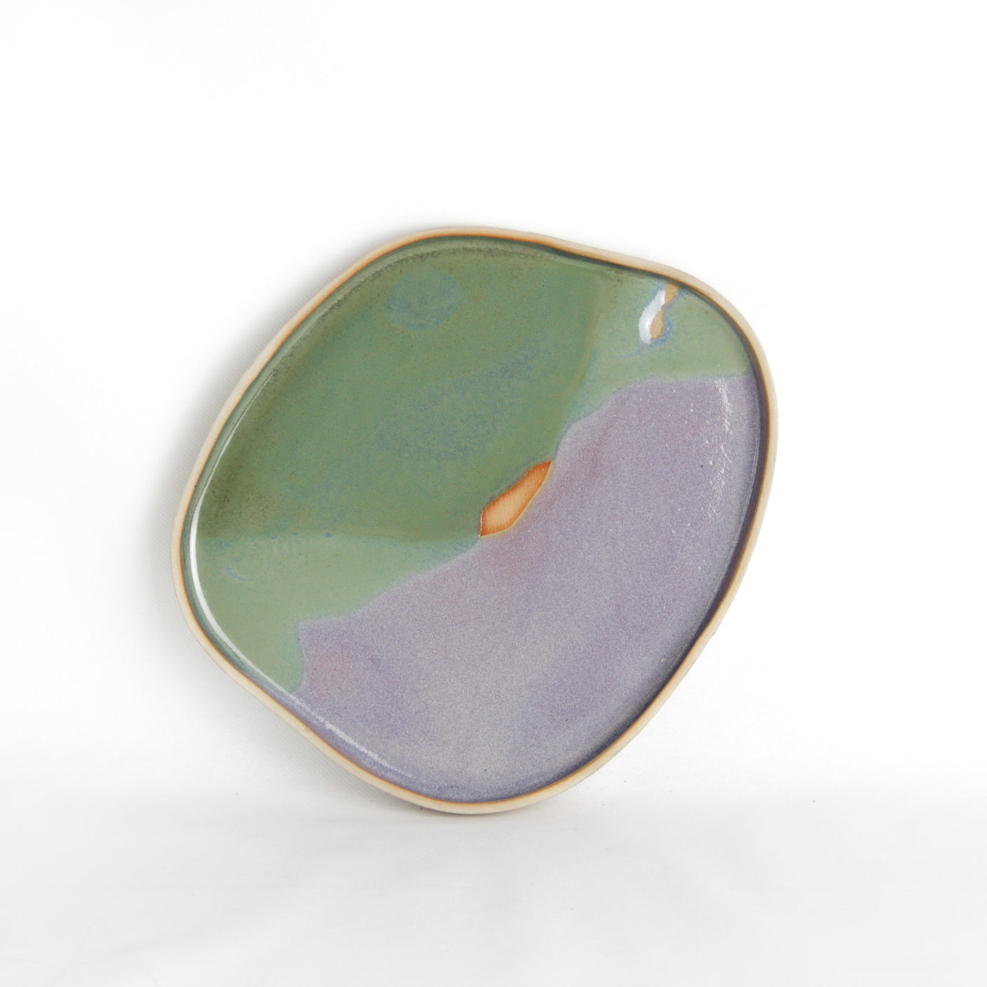 Image d'un plateau en céramique à la forme organique sur fond blanc. Le plateau est bicolore rose et vert.