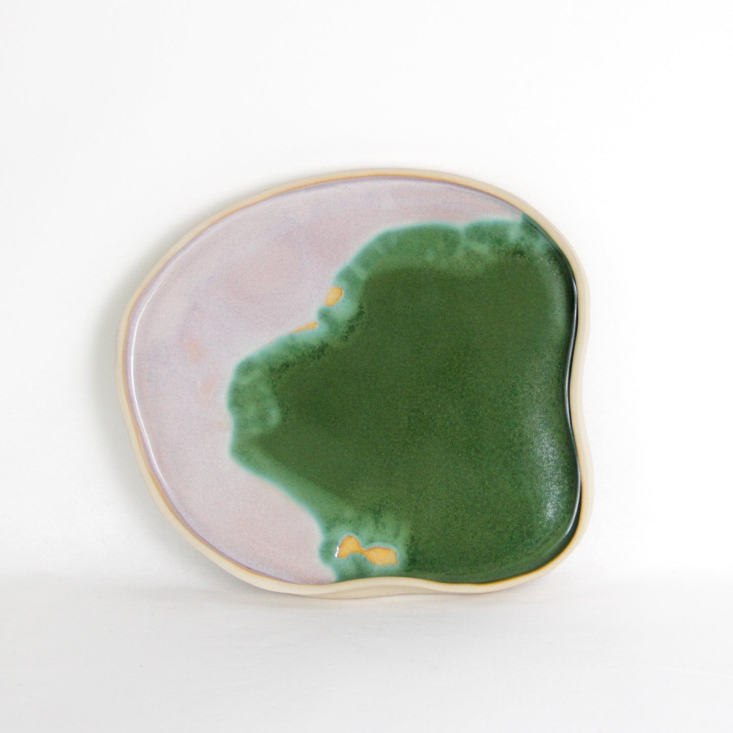 Image d'un plateau vert et rose en céramique artisanale. Sa forme est aléatoire et organique. Il mesure environ 27 cm de diamètre.